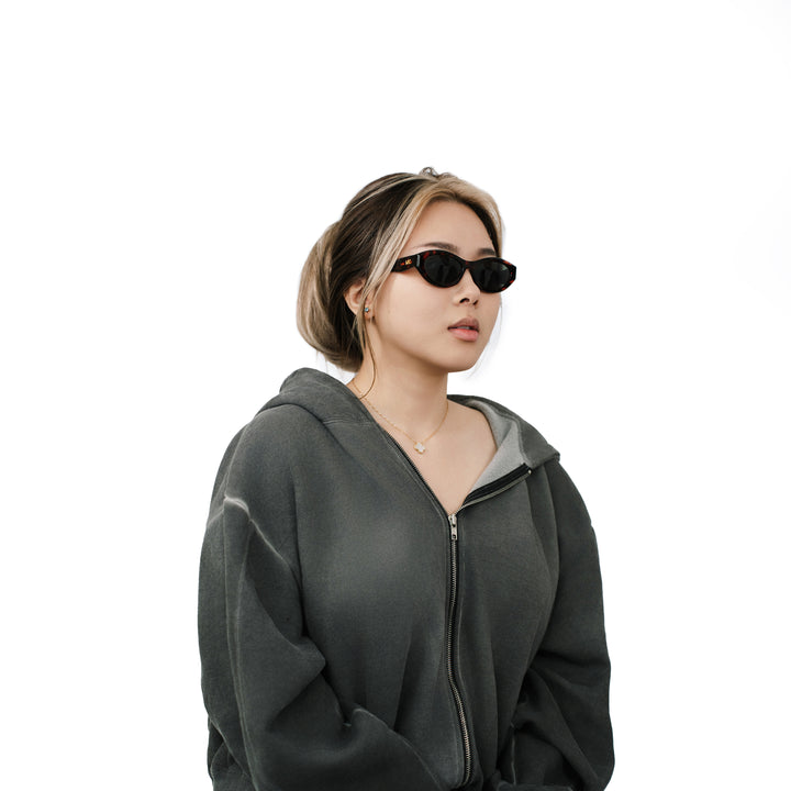 VLIZ Nolita oval sunglasses with tortoise frame and black lenses, featuring smooth oval design and engraved logo on temples.