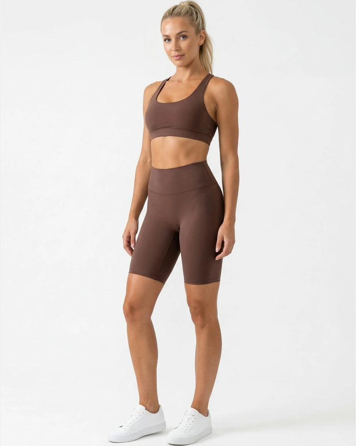 Woman wearing a brown sports bra and shorts set on a white background