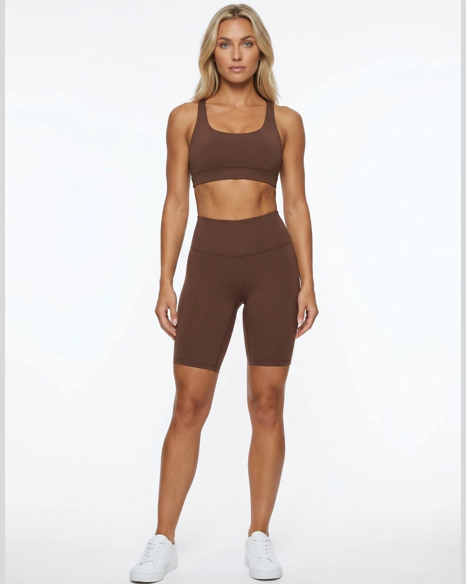 Woman wearing a brown sports bra and shorts set on a white background