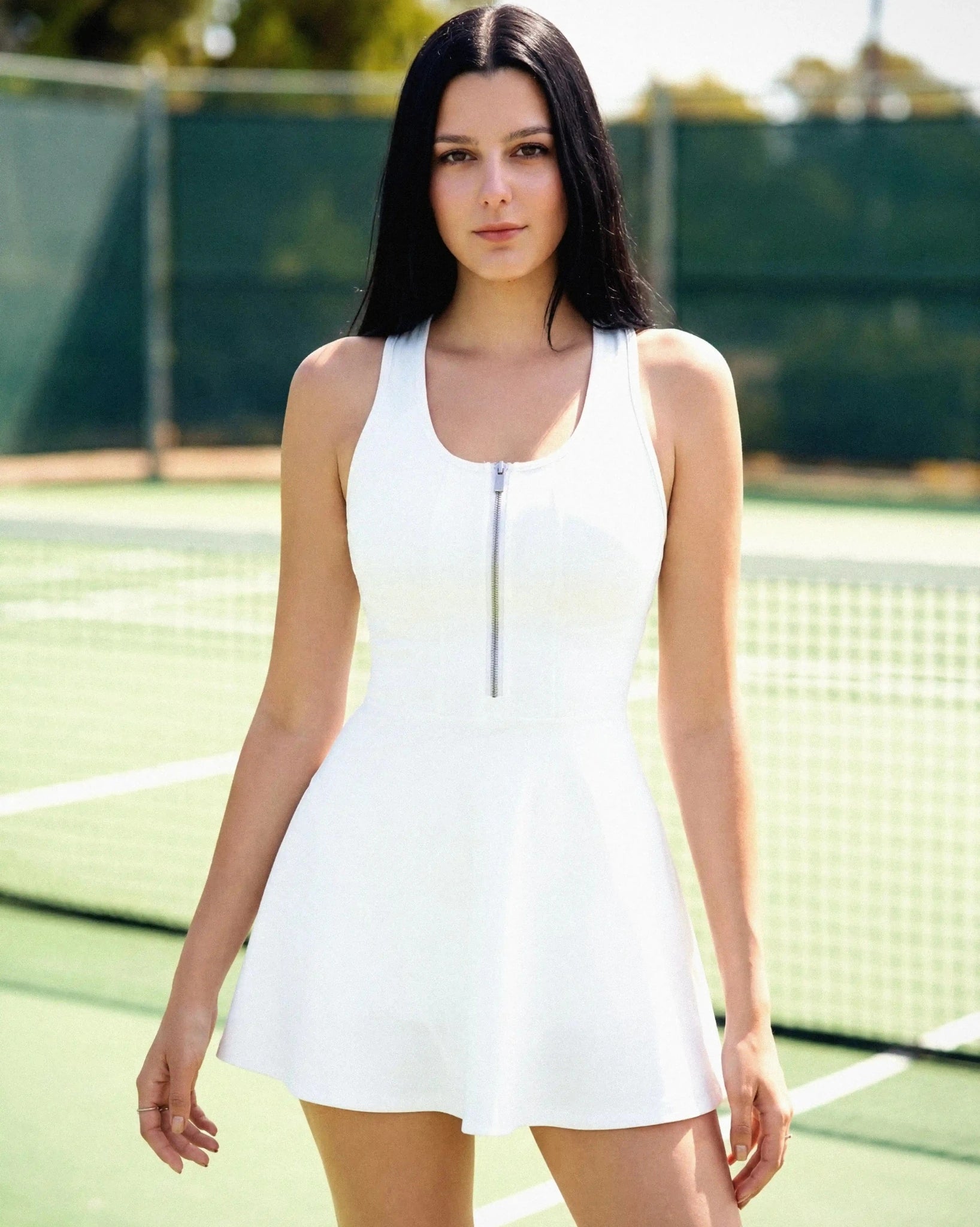 Woman in a white tennis dress standing on a tennis court