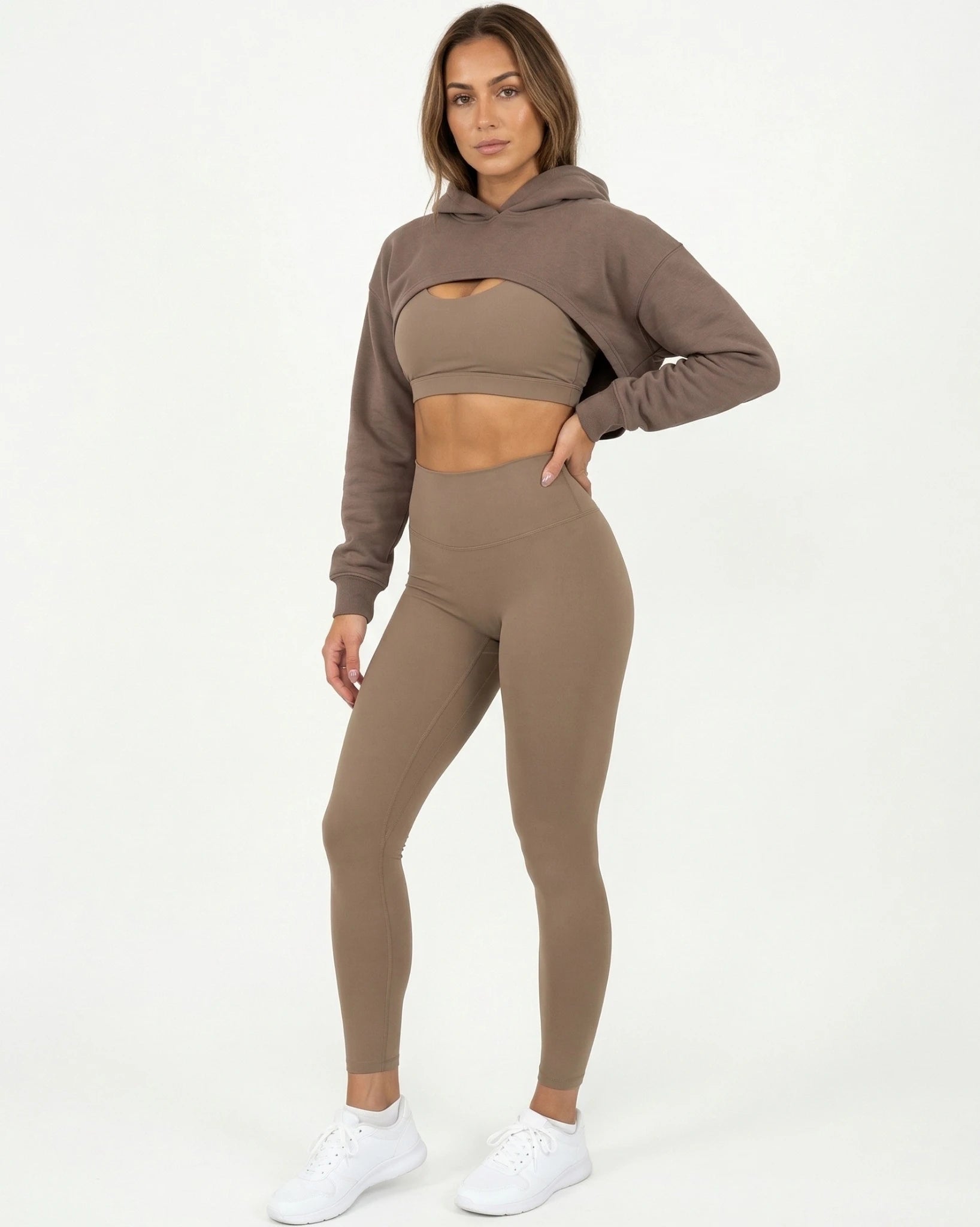 Woman wearing a brown hoodie and leggings set on a white background