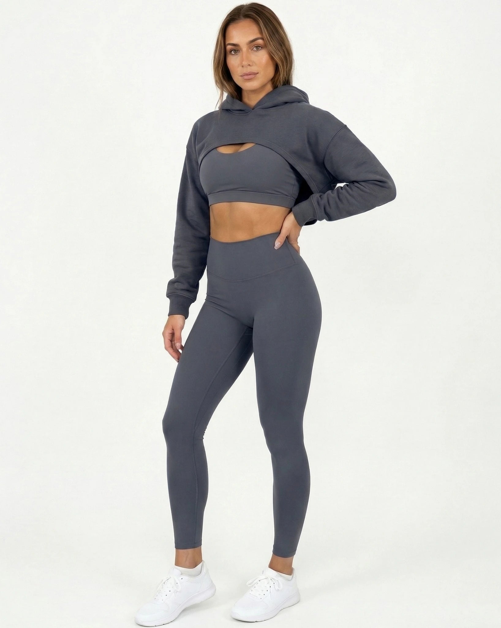 Woman wearing a gray hoodie and leggings set on a white background
