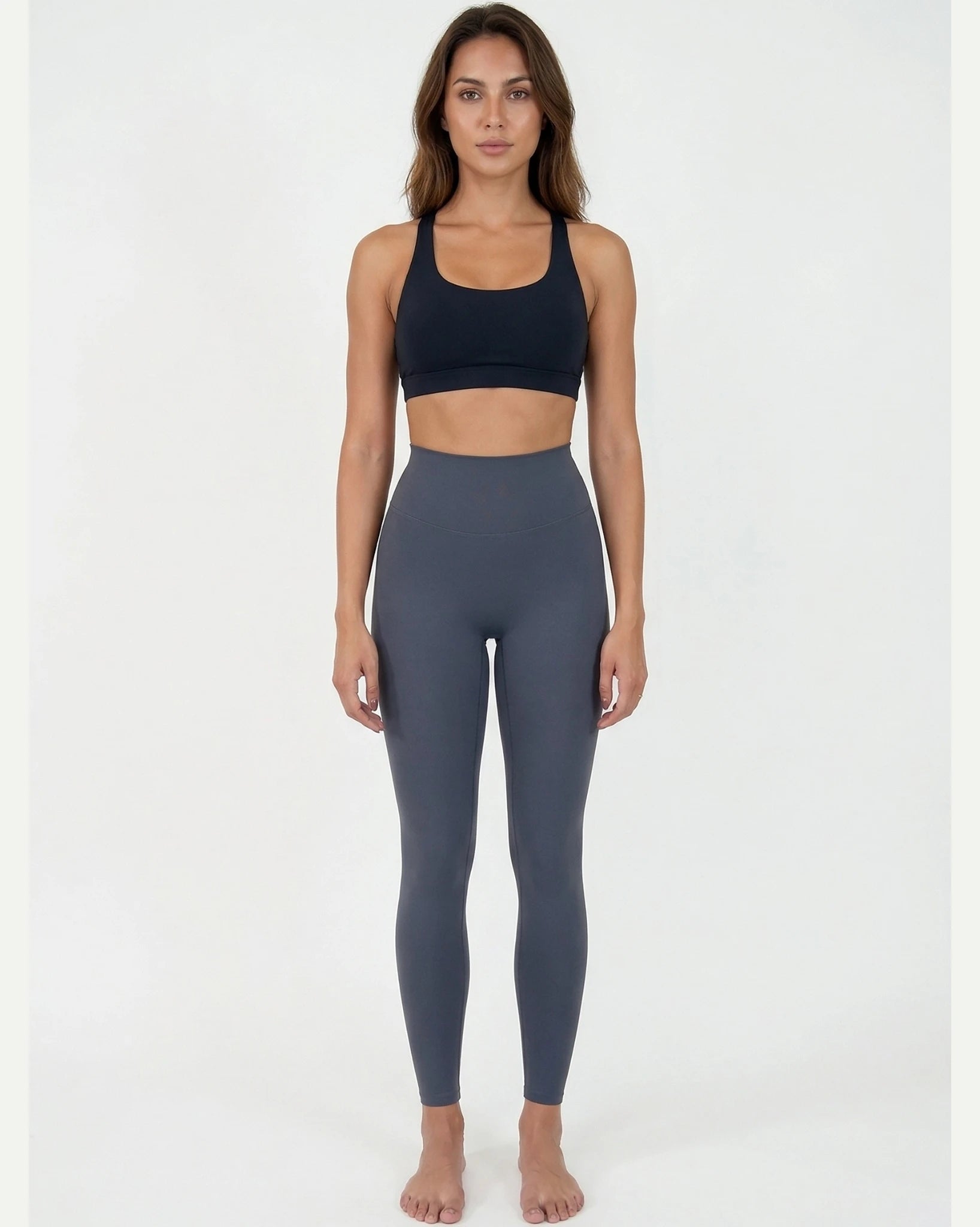 Woman wearing a black sports bra and gray leggings on a white background