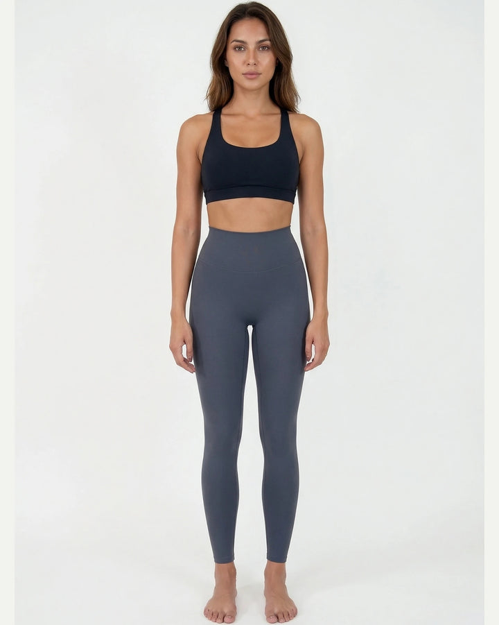 Woman wearing a black sports bra and gray leggings on a white background