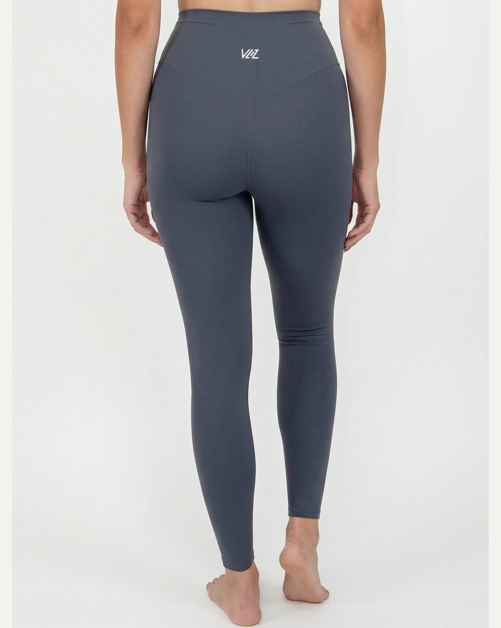 Person wearing dark gray leggings with a brand logo on a white background