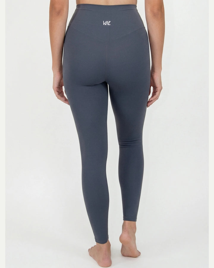 Person wearing dark gray leggings with a brand logo on a white background
