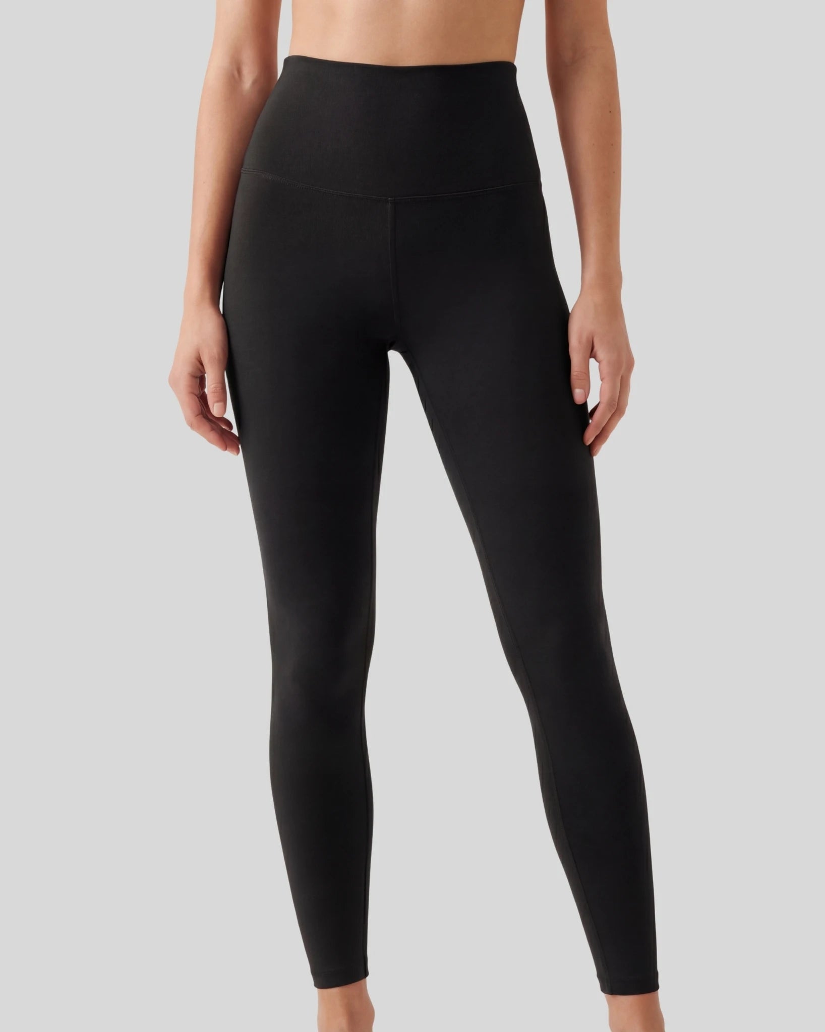 Black leggings worn by a person on a gray background