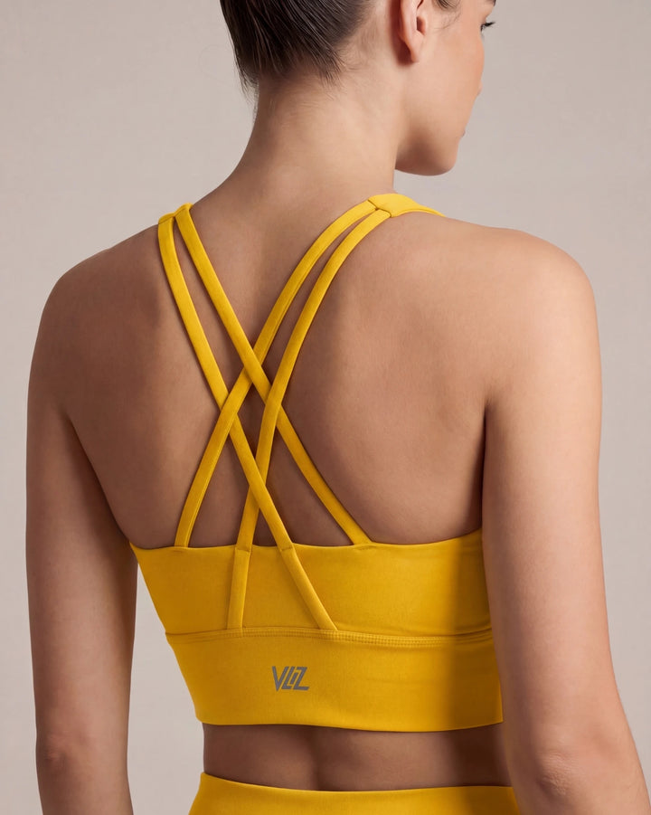 Yellow sports bra with criss-cross back design on a neutral background