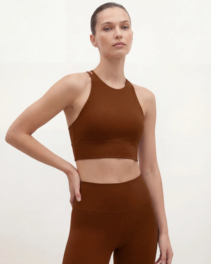 Woman wearing a brown sports bra and leggings on a white background
