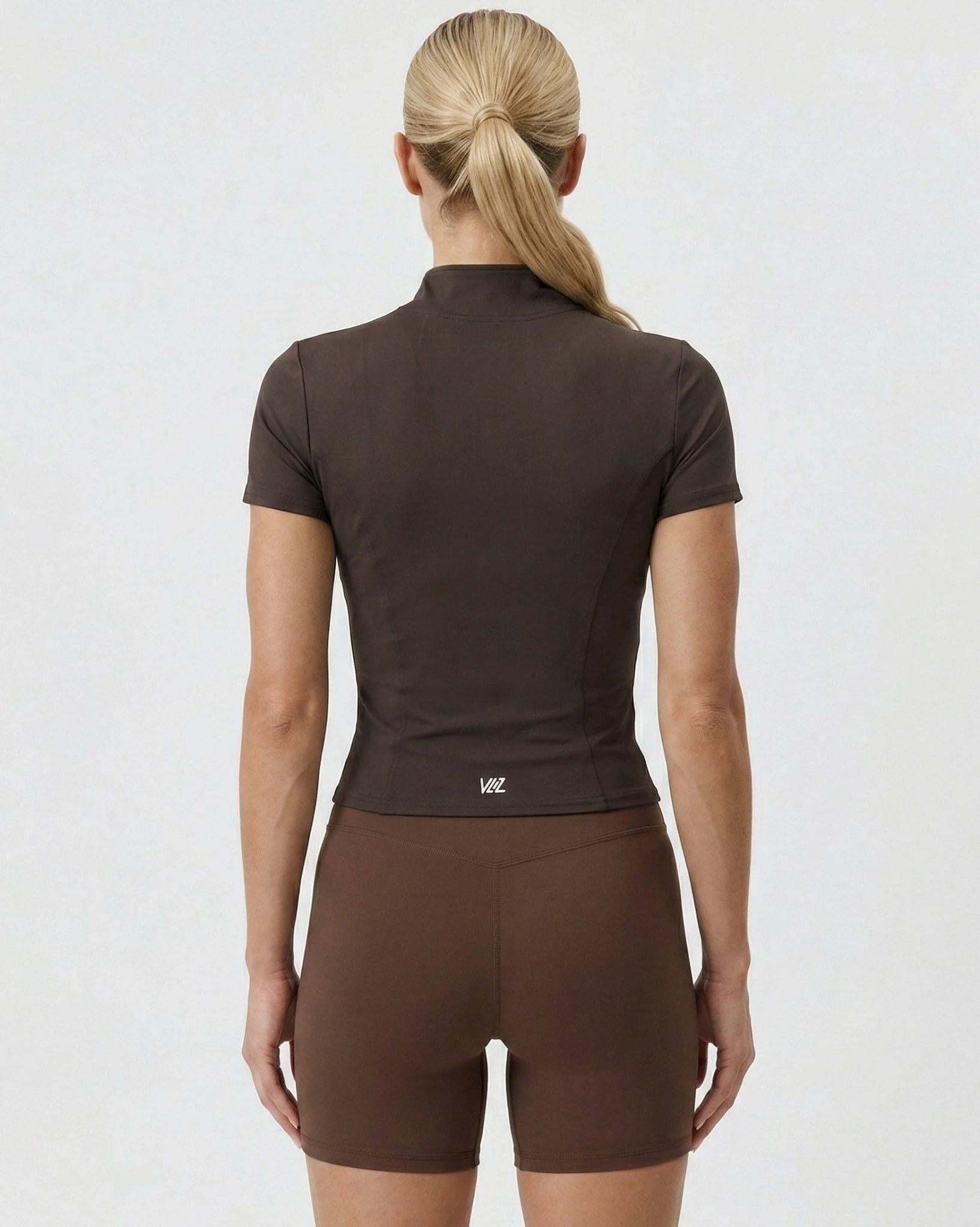 Woman wearing a brown athletic outfit on a white background