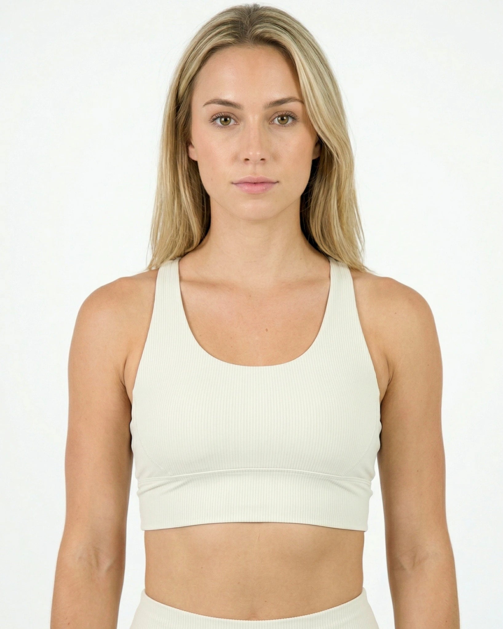 Woman wearing a white sports bra against a plain background
