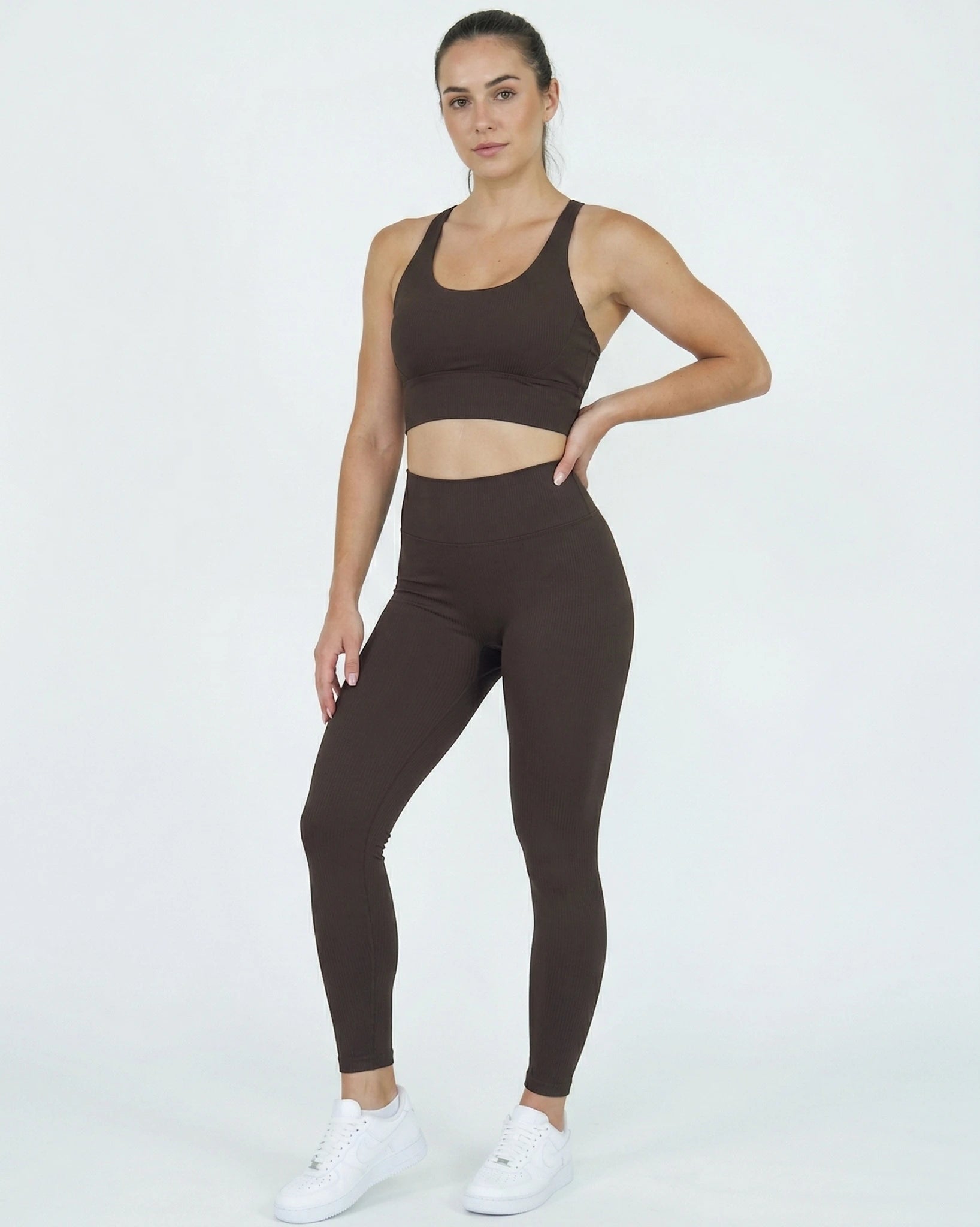 Woman wearing a brown sports bra and leggings set on a white background
