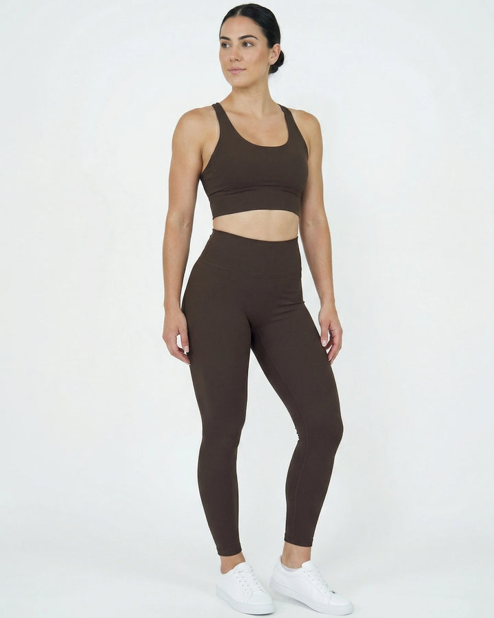 Woman wearing a brown sports bra and leggings set on a white background