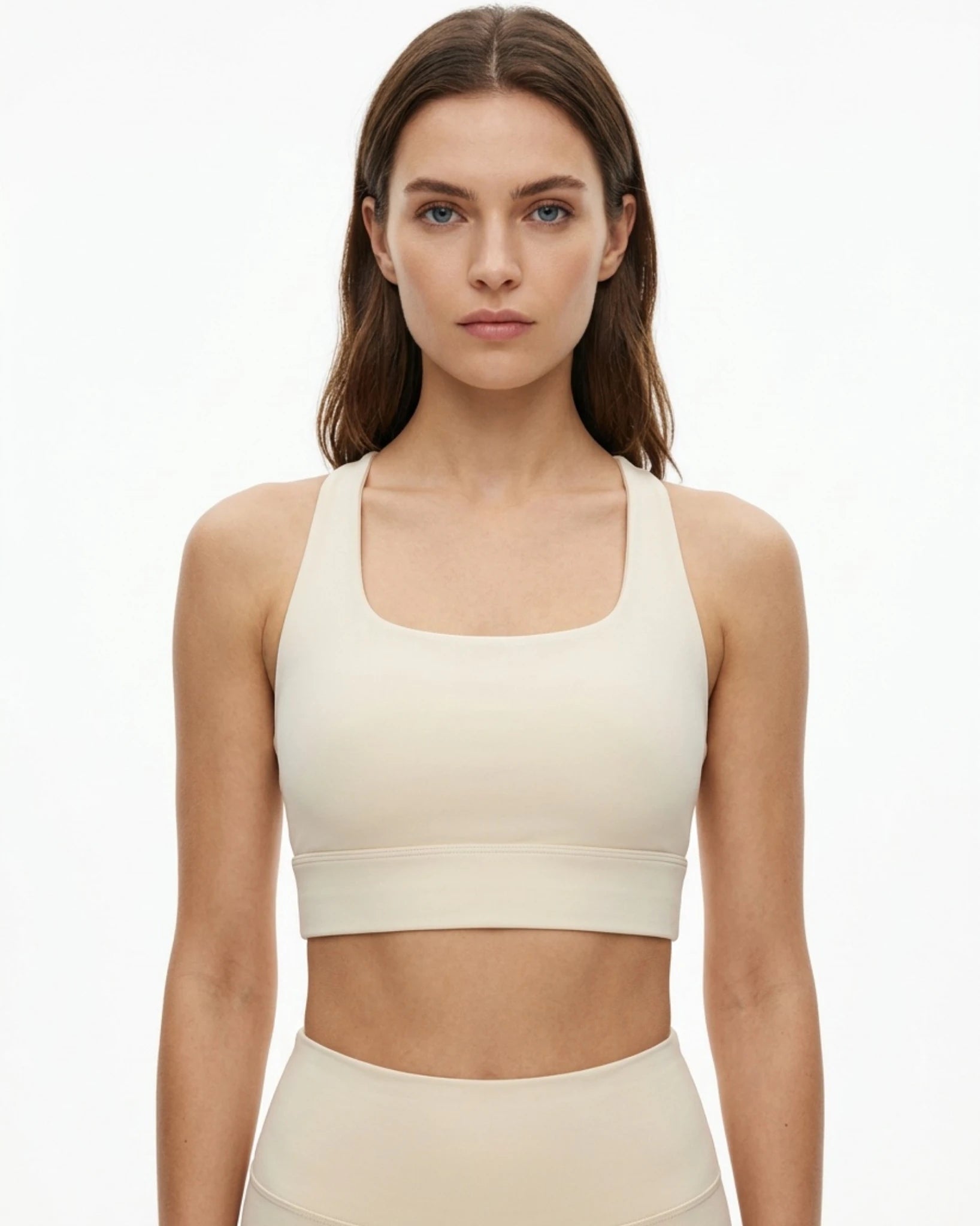 Woman wearing a beige sports bra and leggings on a white background