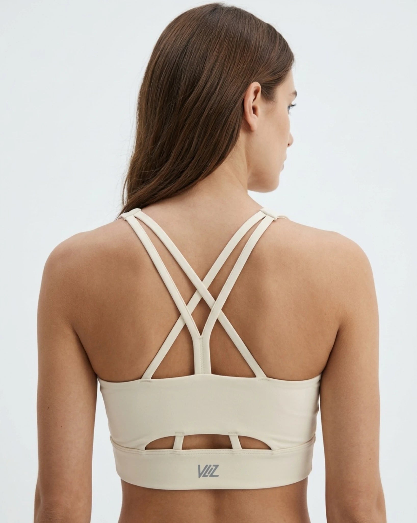 Beige sports bra with criss-cross straps on a plain background