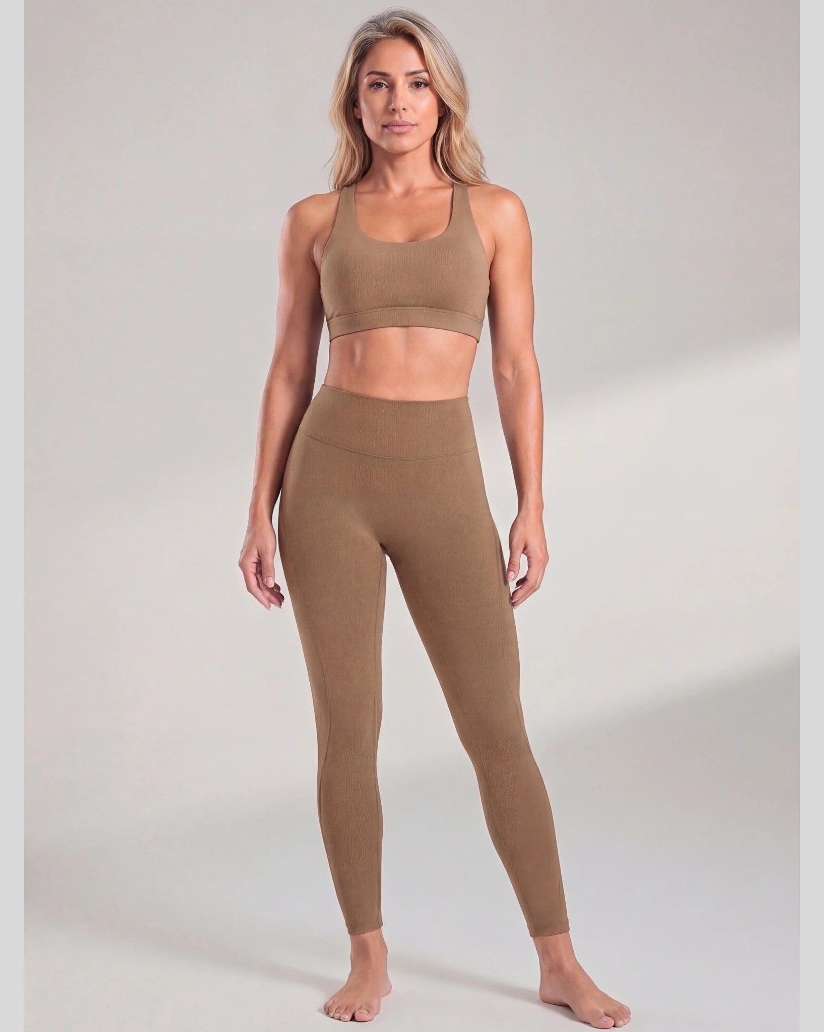 Woman wearing a brown sports bra and leggings set on a plain background