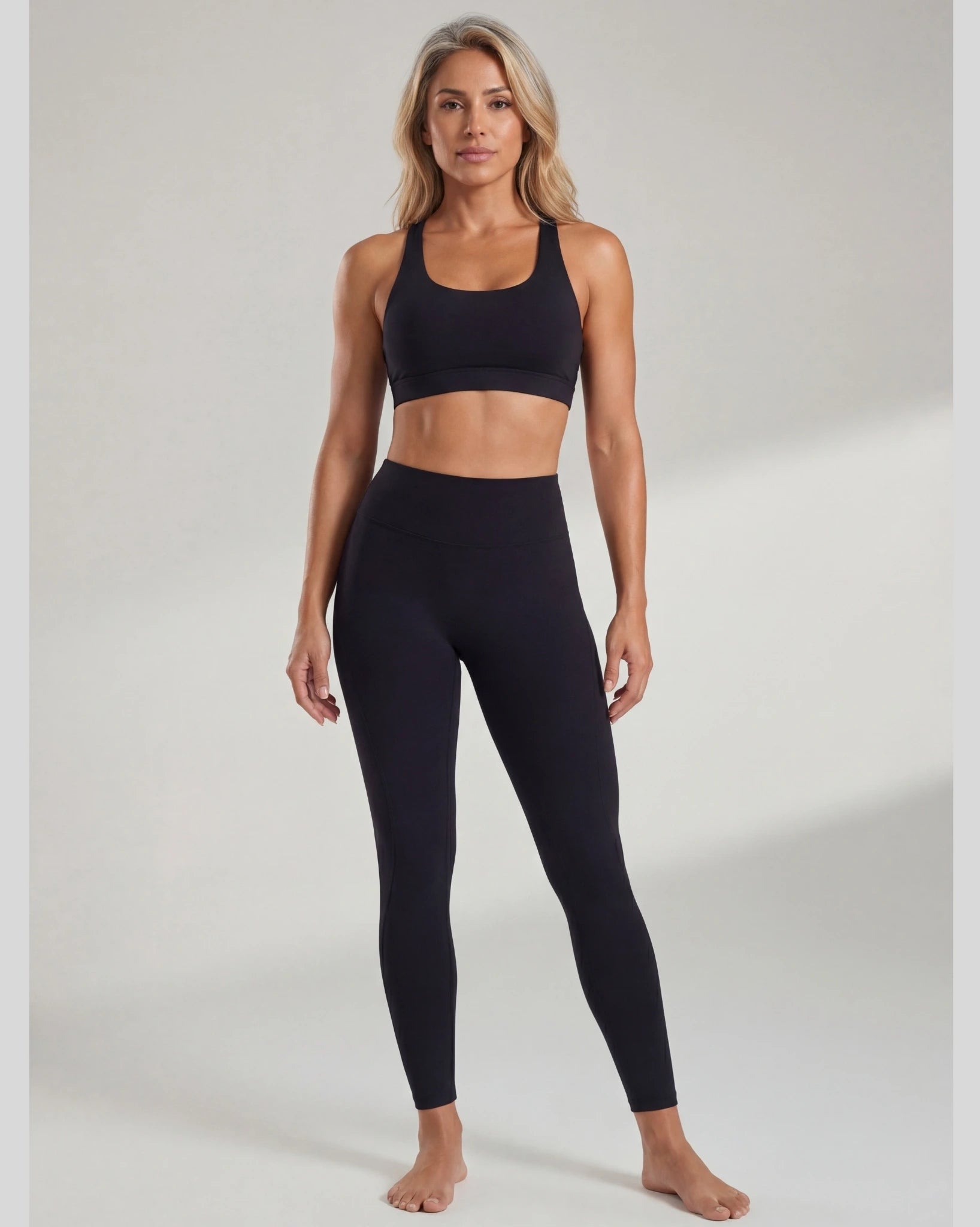 Woman wearing a black sports bra and leggings on a white background