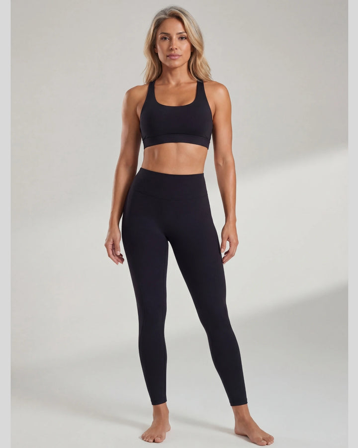 Woman wearing a black sports bra and leggings on a white background