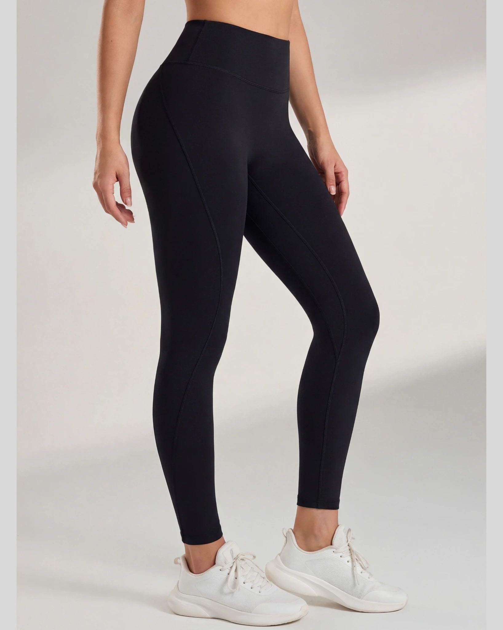 Person wearing black leggings and white sneakers on a light gray background