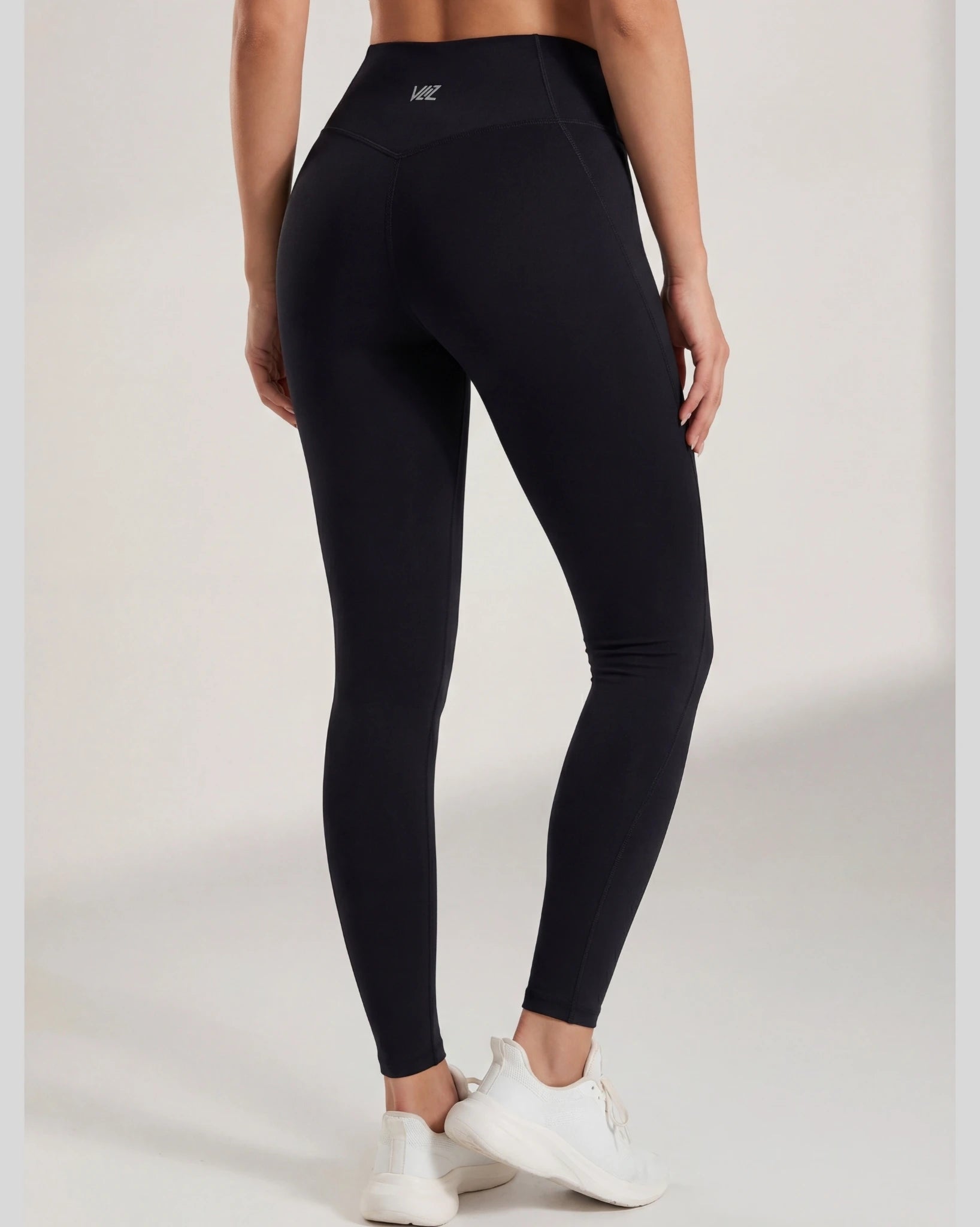 Person wearing black leggings with a visible brand logo on a white background