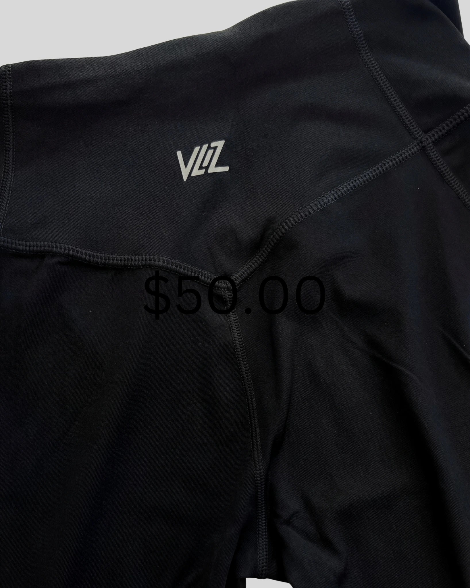 Black athletic outfit with a brand logo and price tag on a light gray background