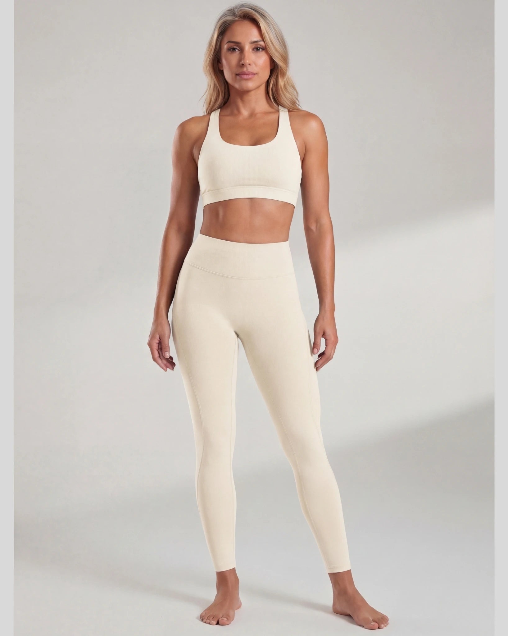 Woman wearing a beige sports bra and leggings set on a plain background