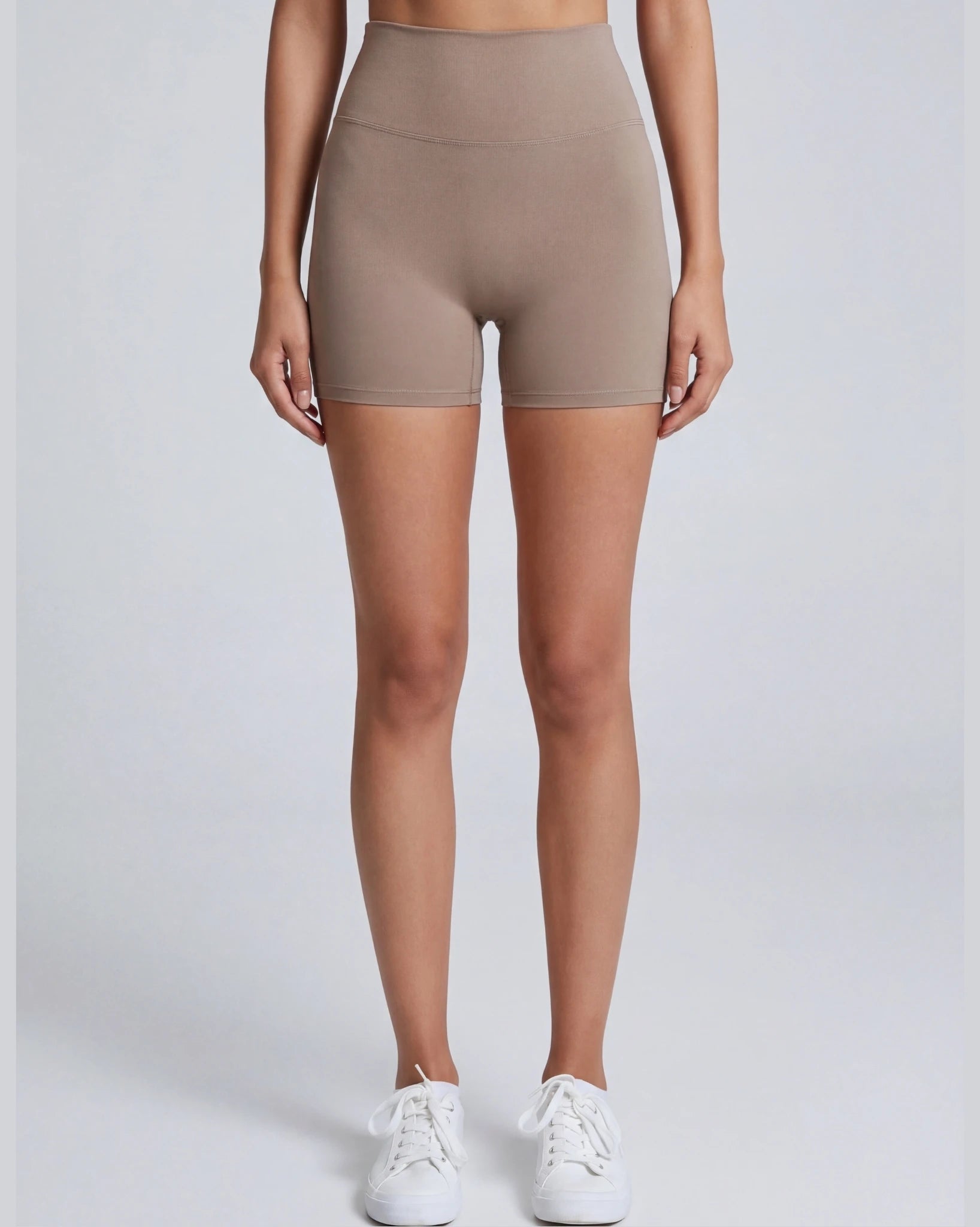 Person wearing beige high-waisted shorts on a white background