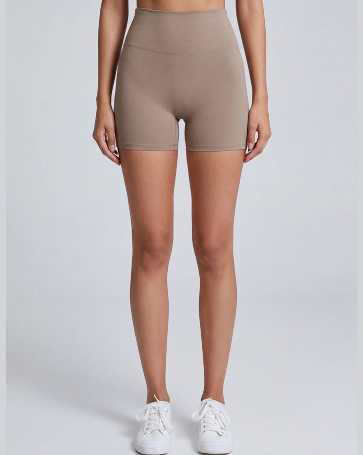 Person wearing beige high-waisted shorts on a white background