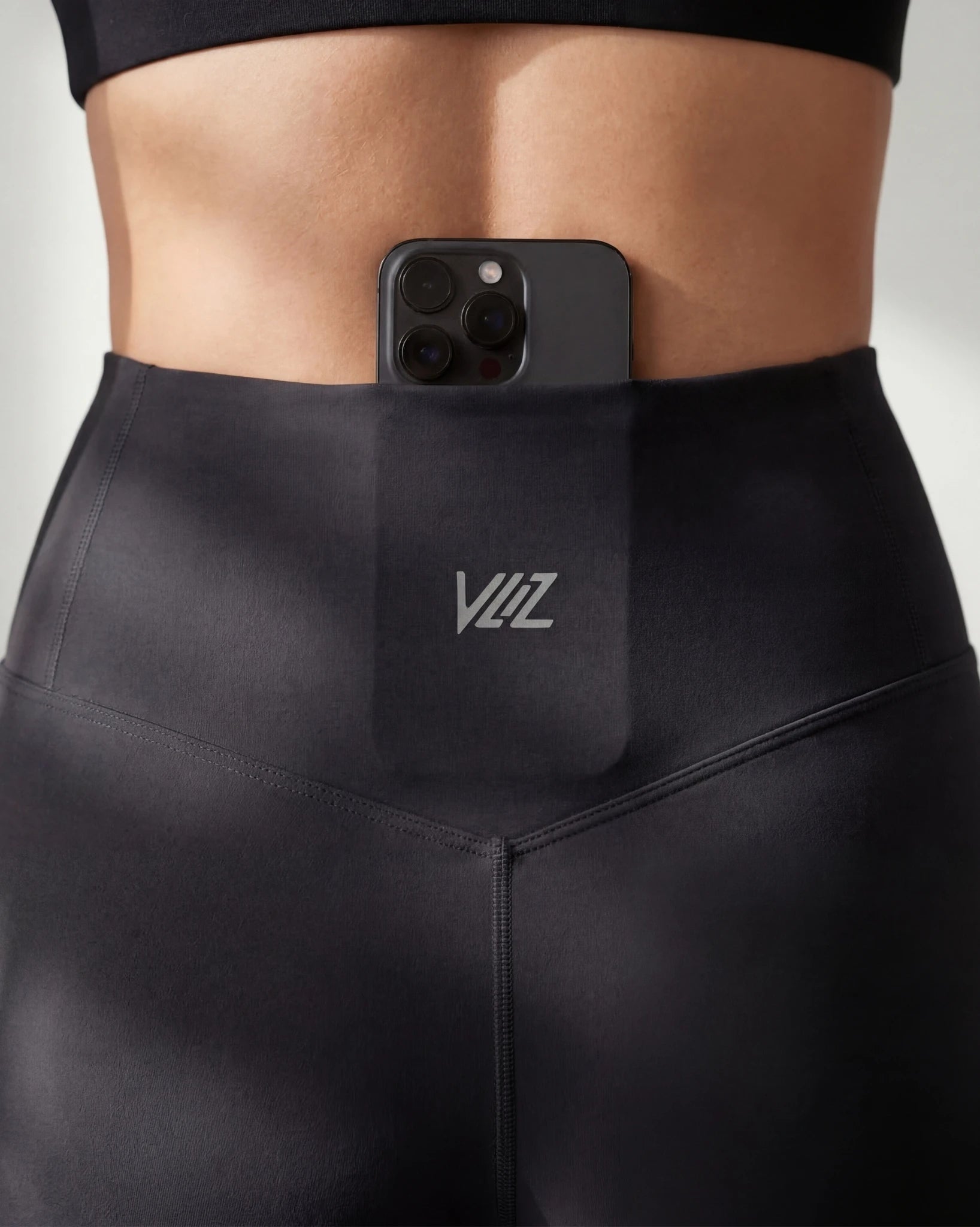 Person wearing black leggings with a phone case featuring 'YIZ' branding.
