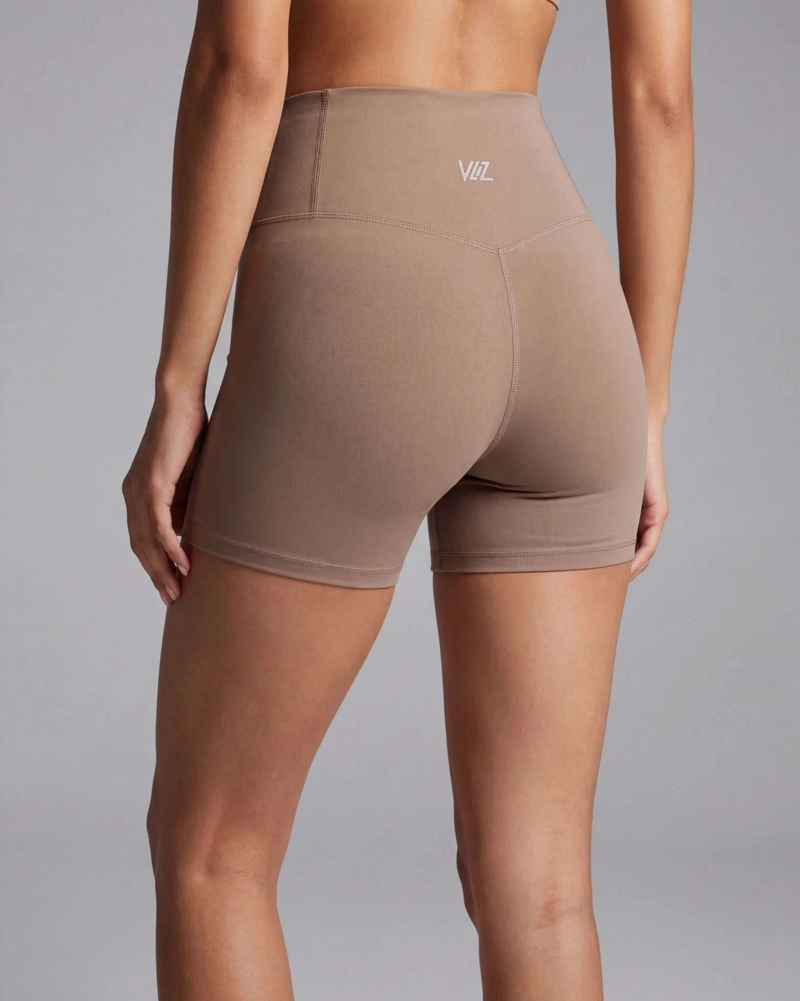 Brown high-waisted shorts with a logo on a gray background