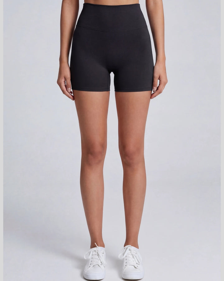 Person wearing black high-waisted shorts on a plain background