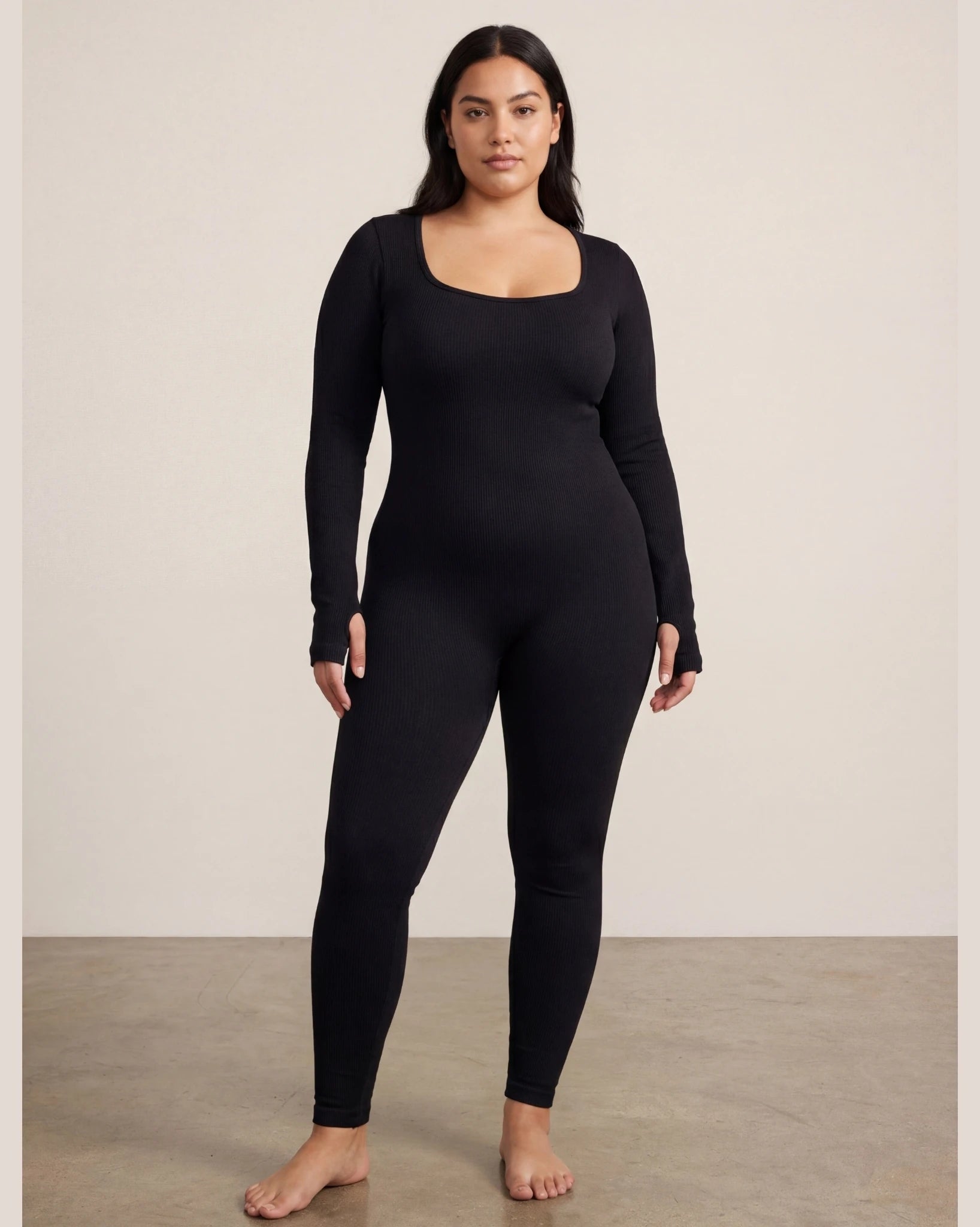 Person wearing a black long-sleeve top and leggings against a plain background