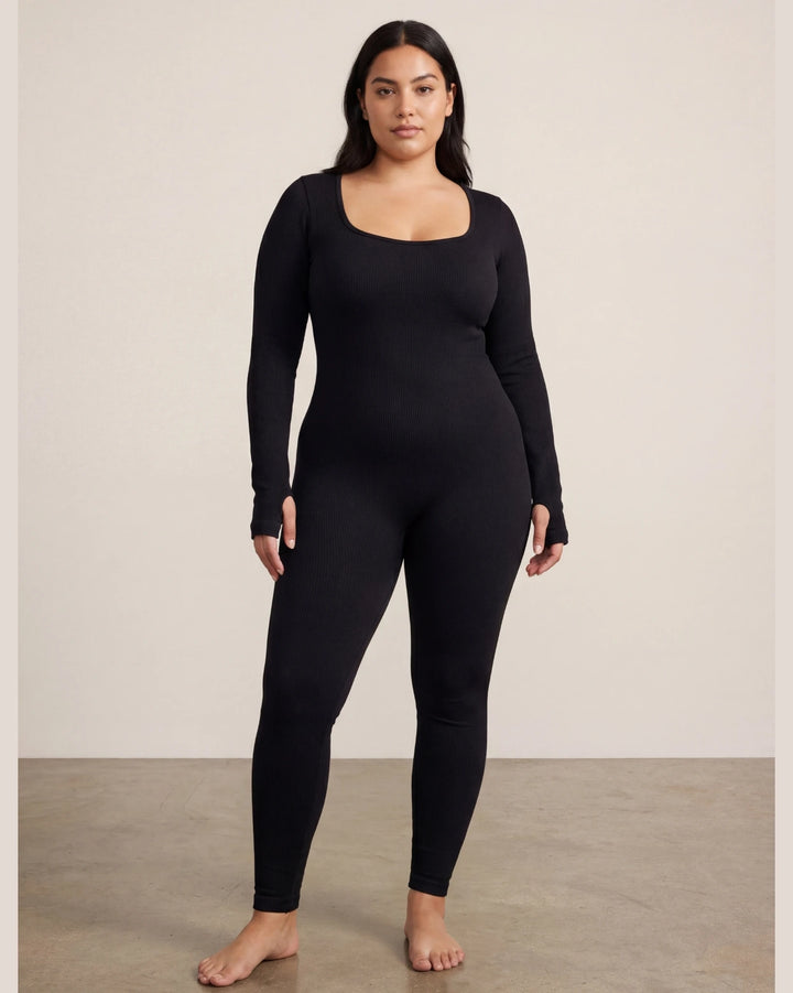 Person wearing a black long-sleeve top and leggings against a plain background