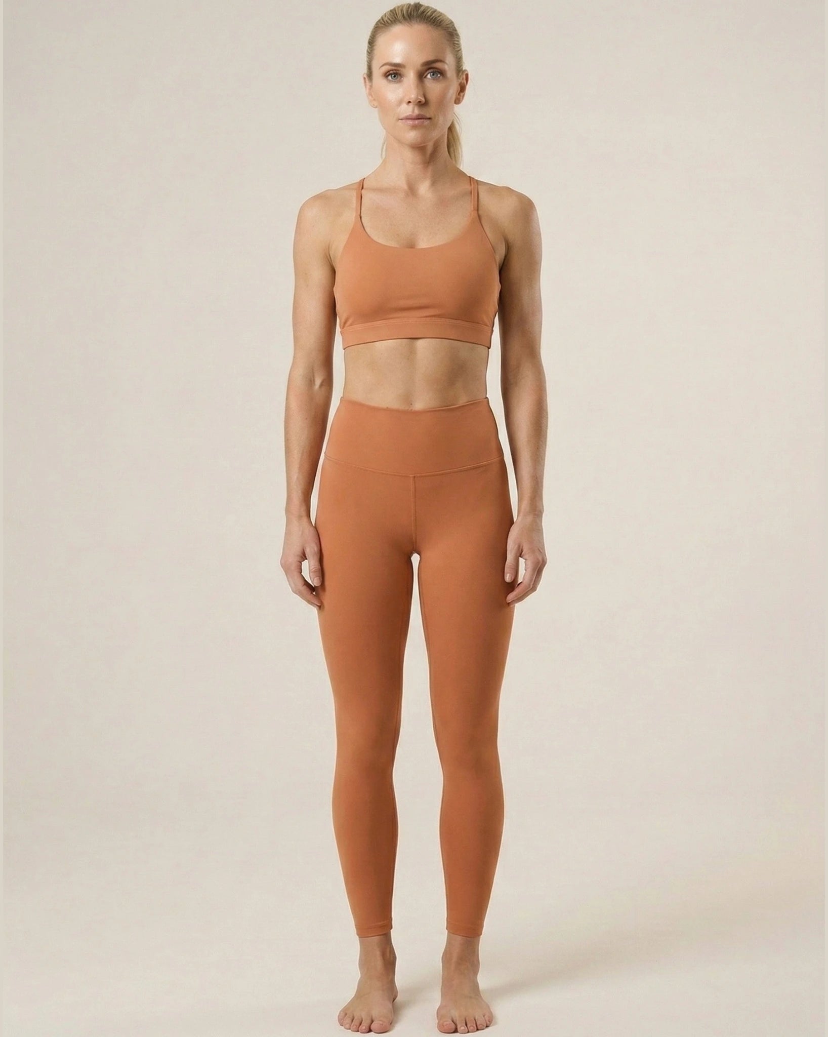 Woman wearing a brown sports bra and leggings on a beige background