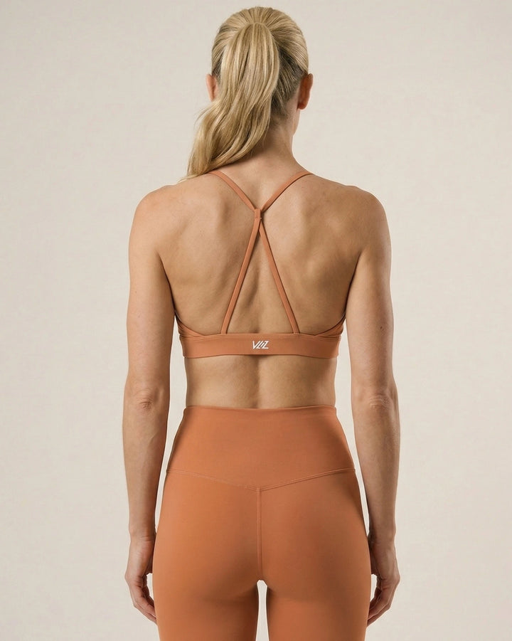Person wearing a brown sports bra and leggings set on a beige background