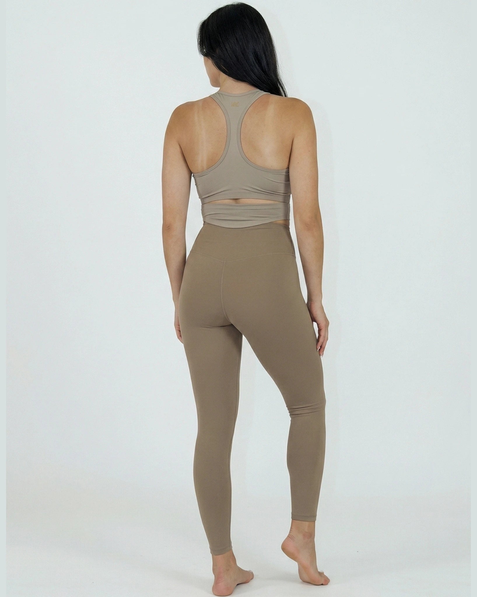 Person wearing a beige sports bra and leggings on a white background
