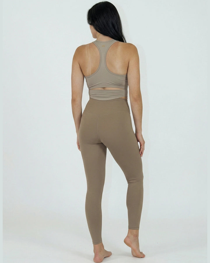 Person wearing a beige sports bra and leggings on a white background