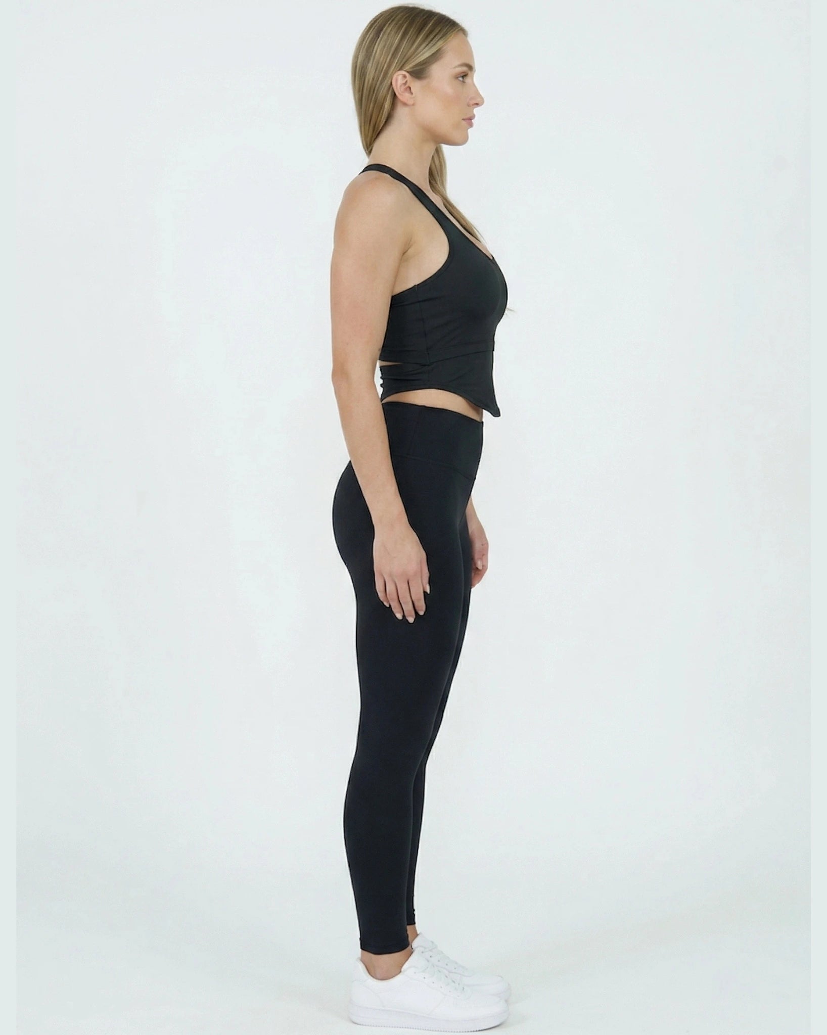 Woman wearing a black crop top and leggings on a white background