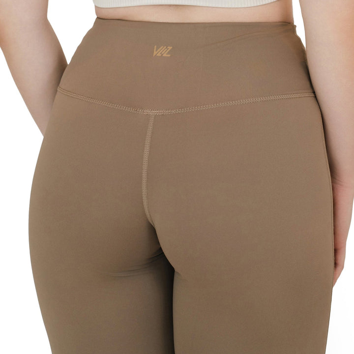 Back view of VLIZ High-Rise Sculpting Flare Leggings in light brown, showcasing logo detail and contoured seam design.