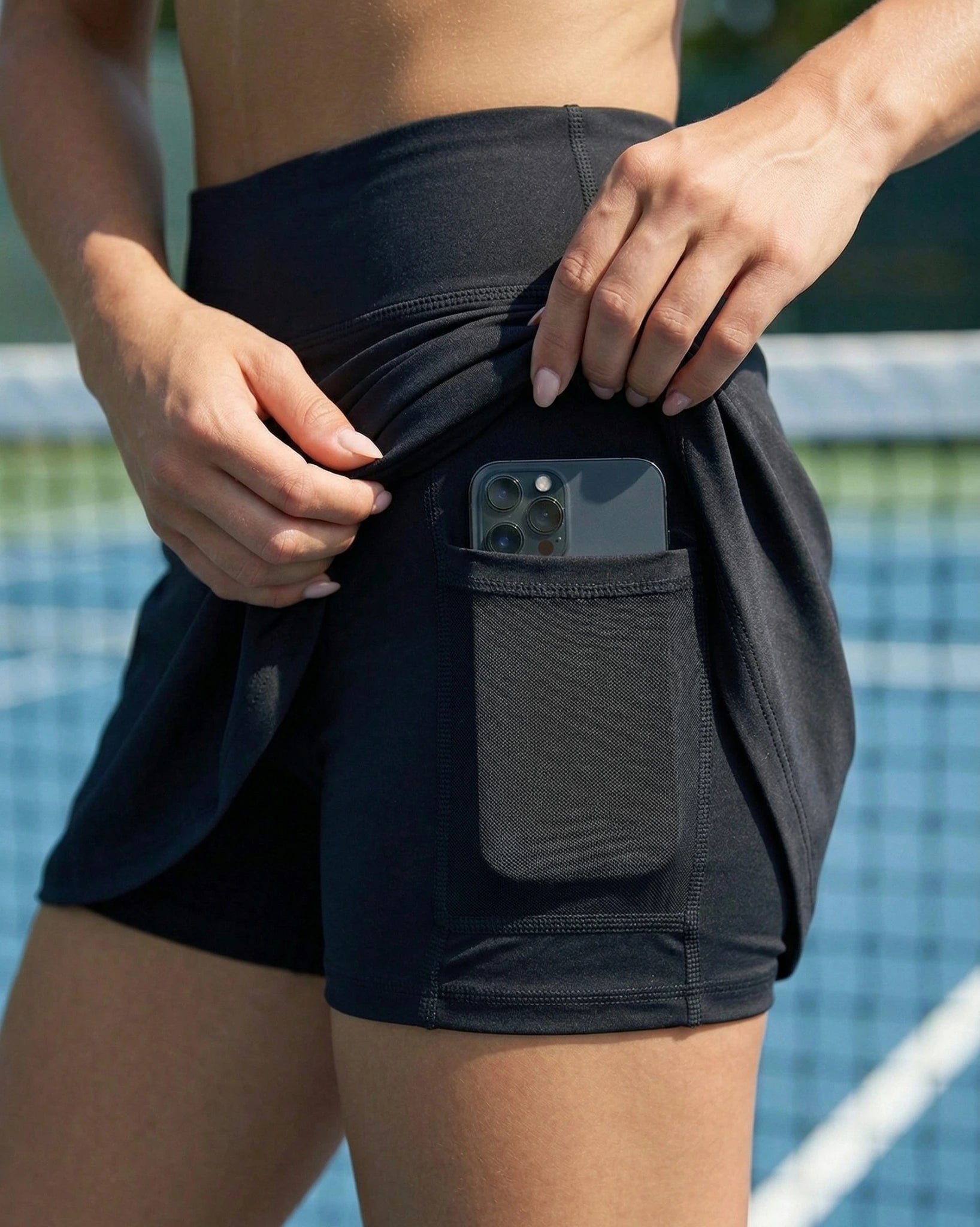 Person wearing black athletic shorts with a pocket on a tennis court