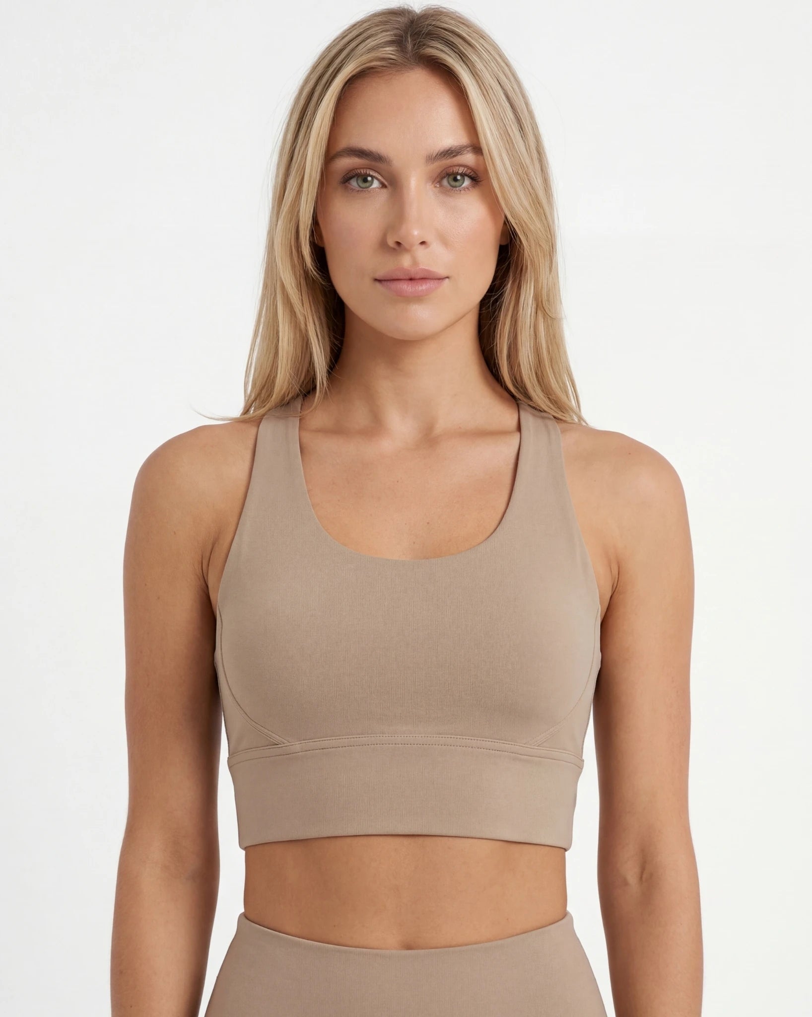 Woman wearing a beige sports bra and leggings on a white background