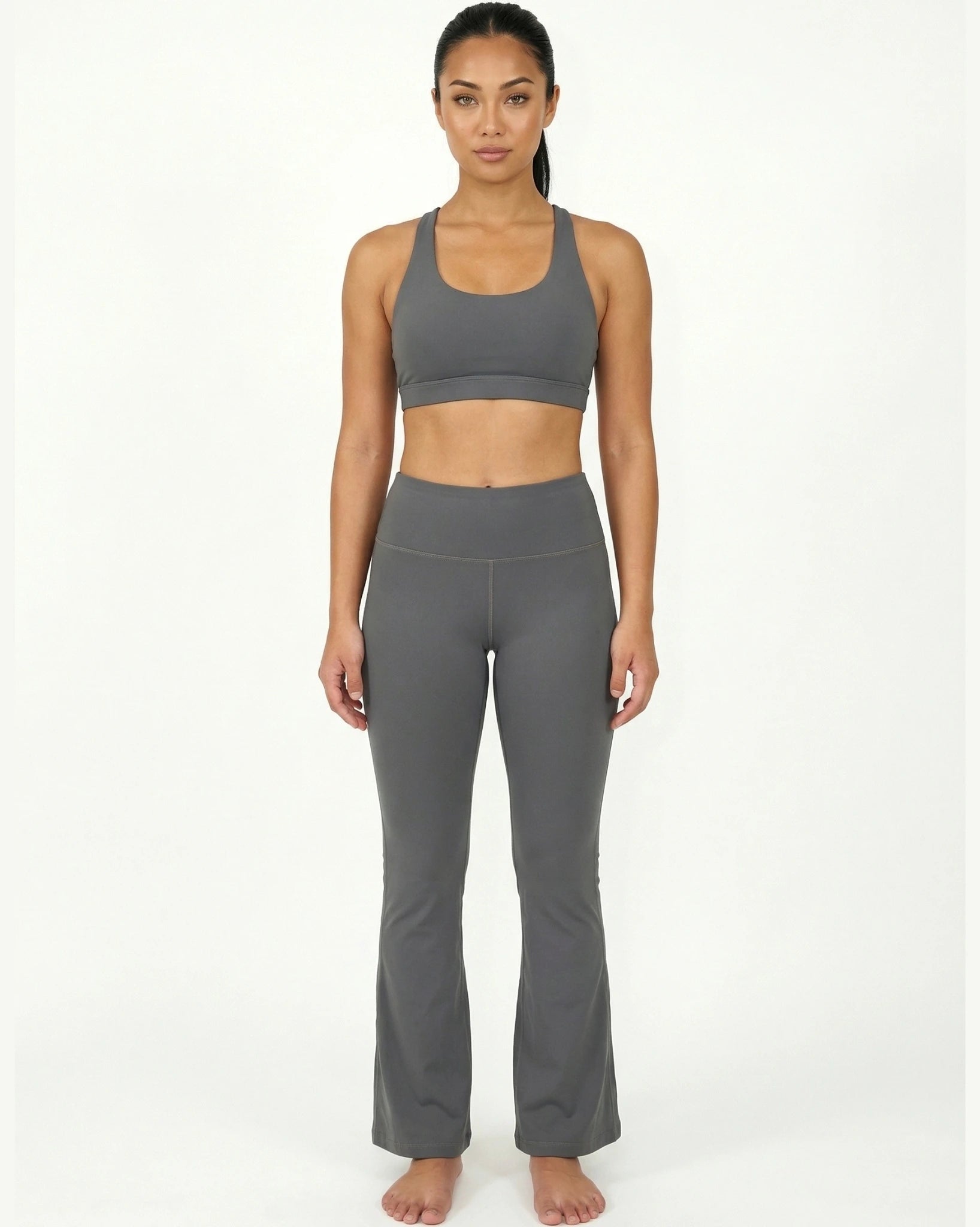 Woman wearing a gray sports bra and leggings on a white background