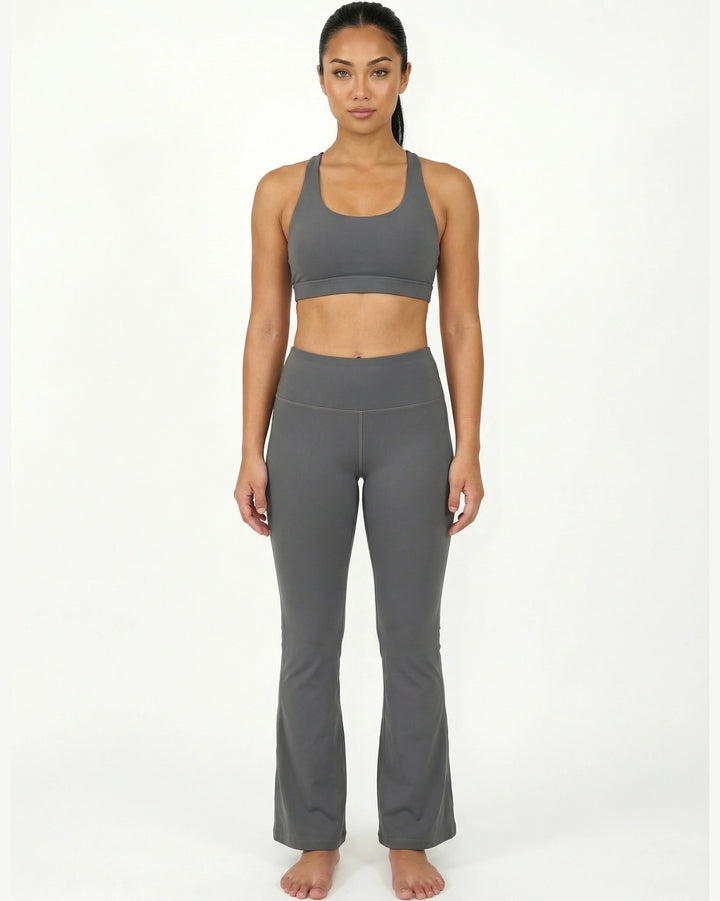 Woman wearing a gray sports bra and leggings on a white background
