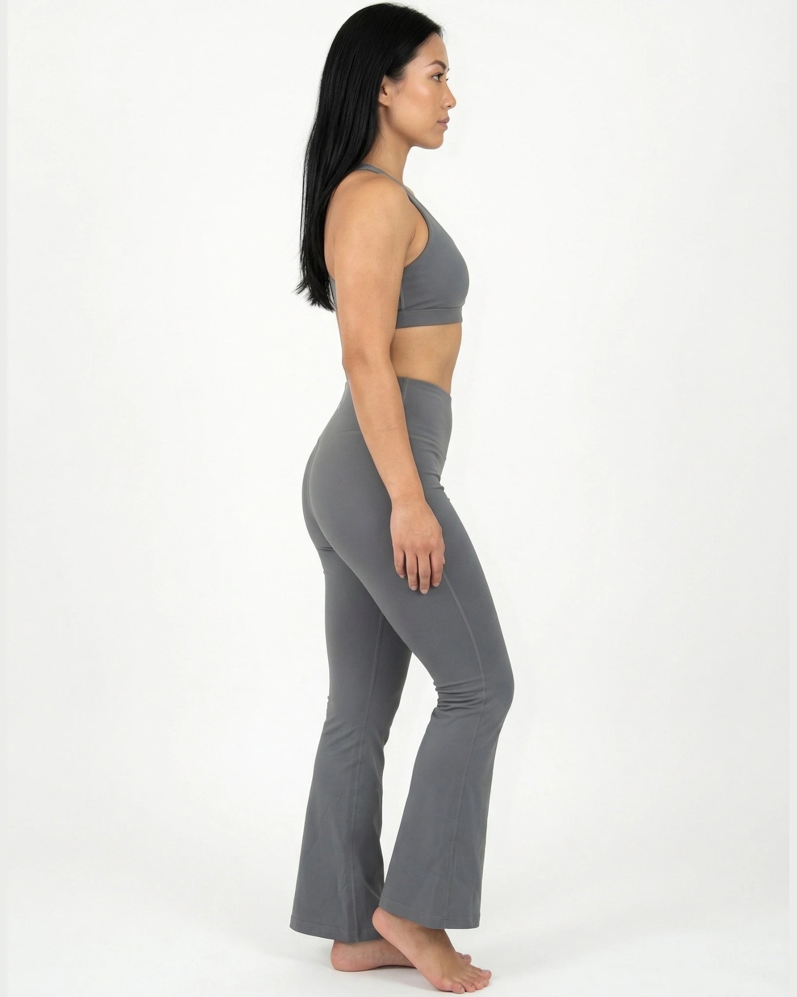 Woman wearing a gray sports bra and leggings set on a white background