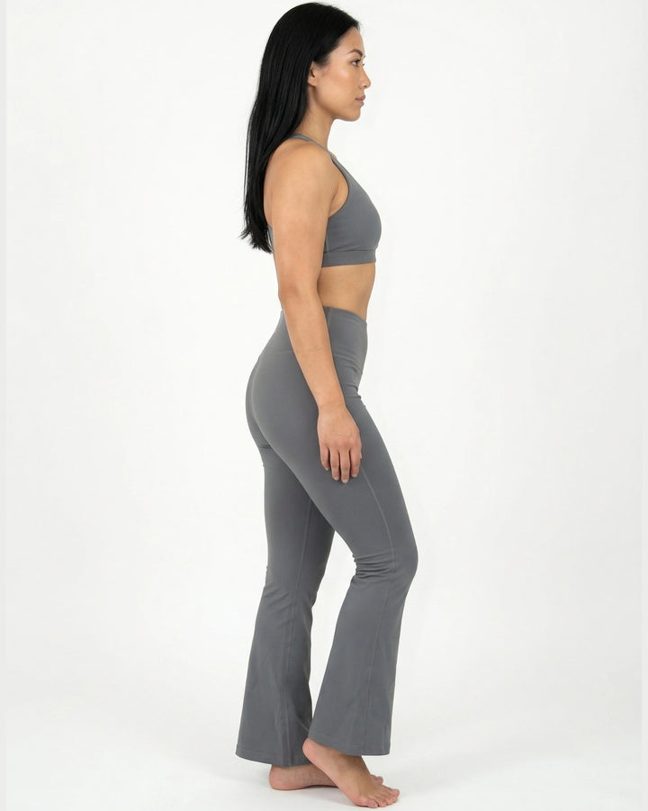 Woman wearing a gray sports bra and leggings set on a white background