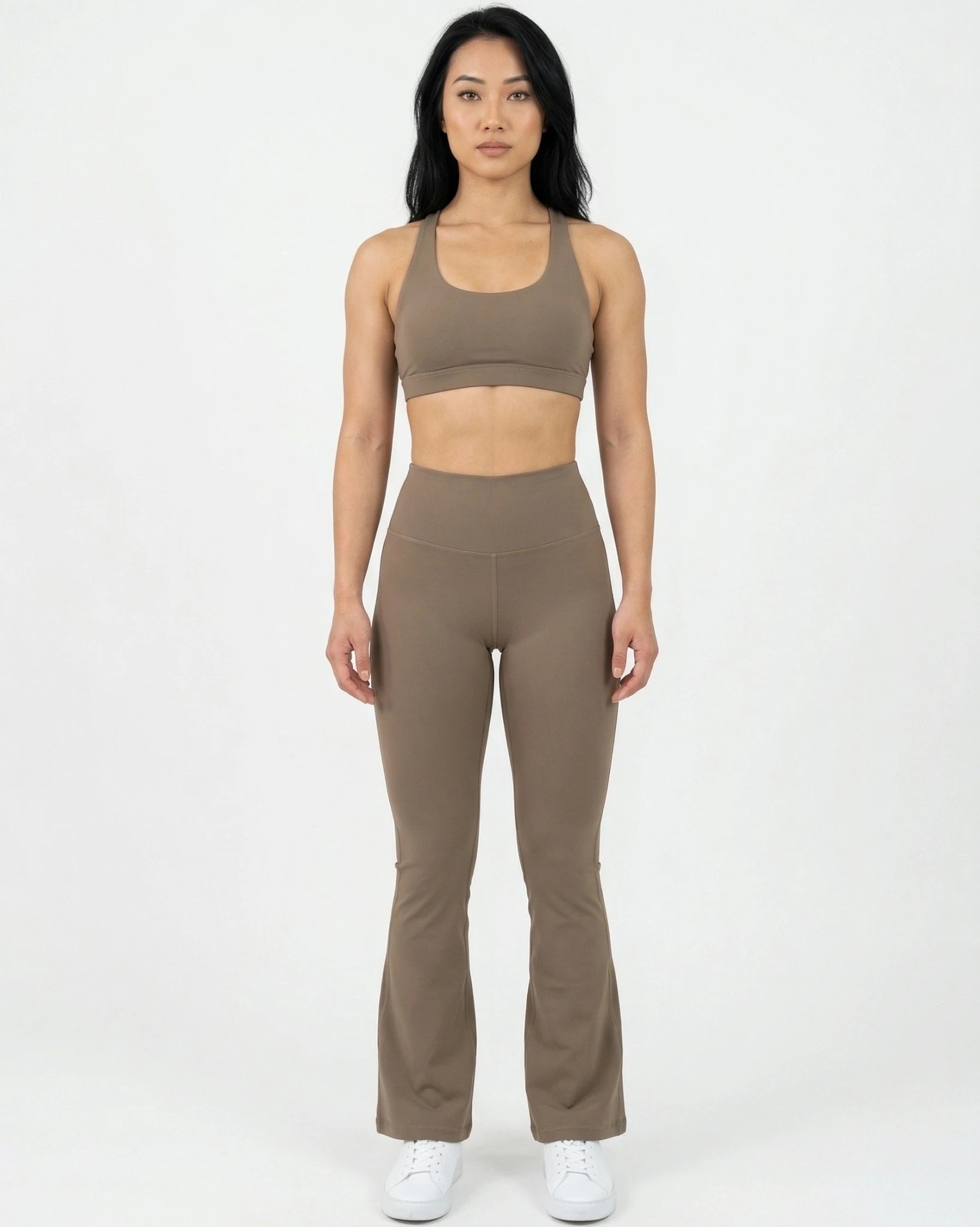 Woman wearing a brown sports bra and leggings set on a white background