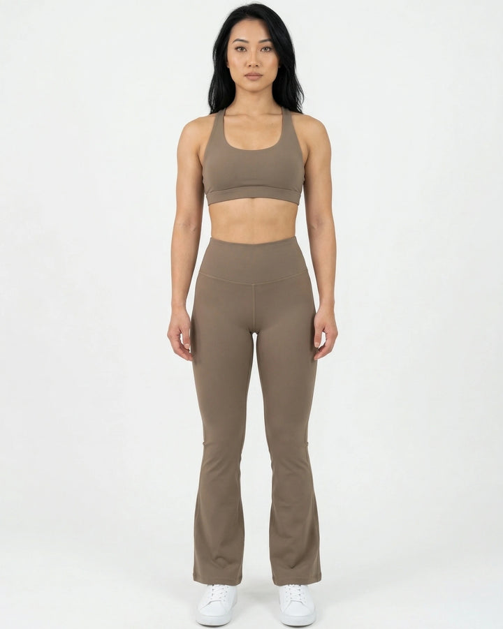 Woman wearing a brown sports bra and leggings set on a white background