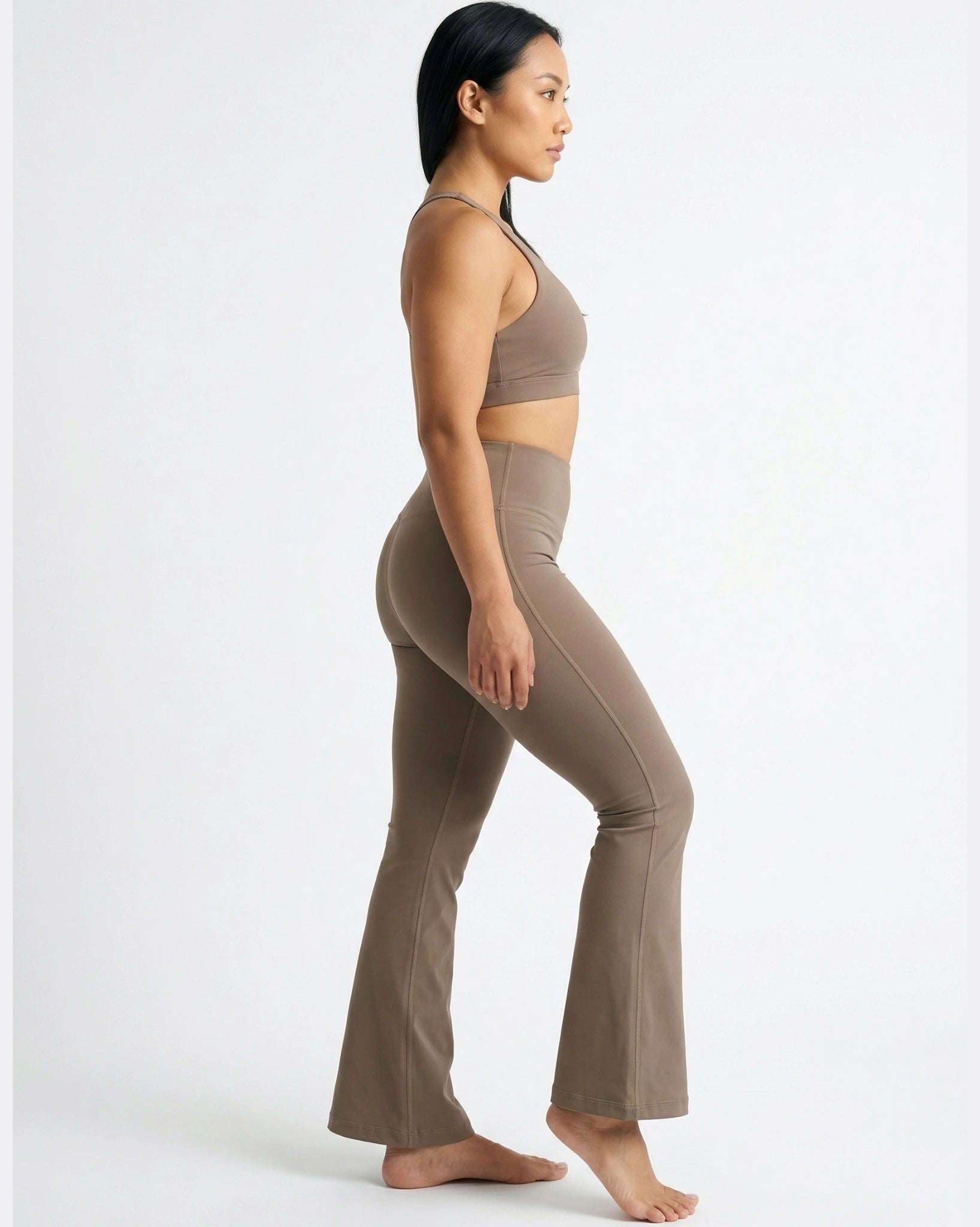 Woman wearing a brown sports bra and leggings set on a white background