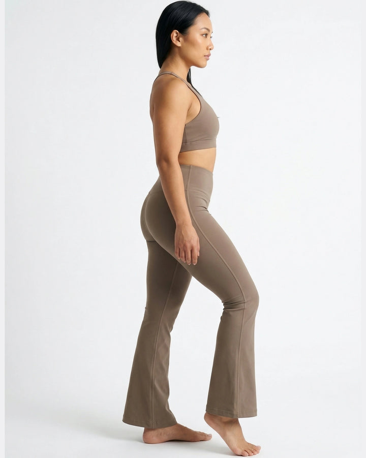 Woman wearing a brown sports bra and leggings set on a white background