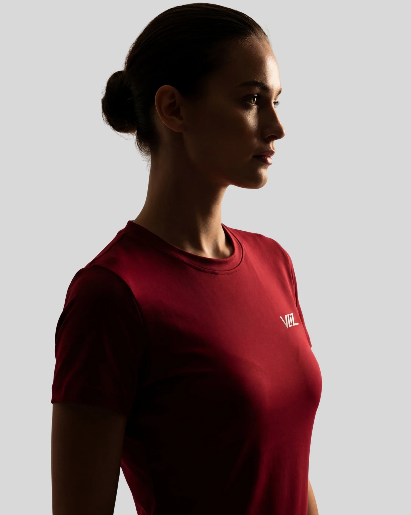 Woman wearing a red t-shirt with a logo on a gray background